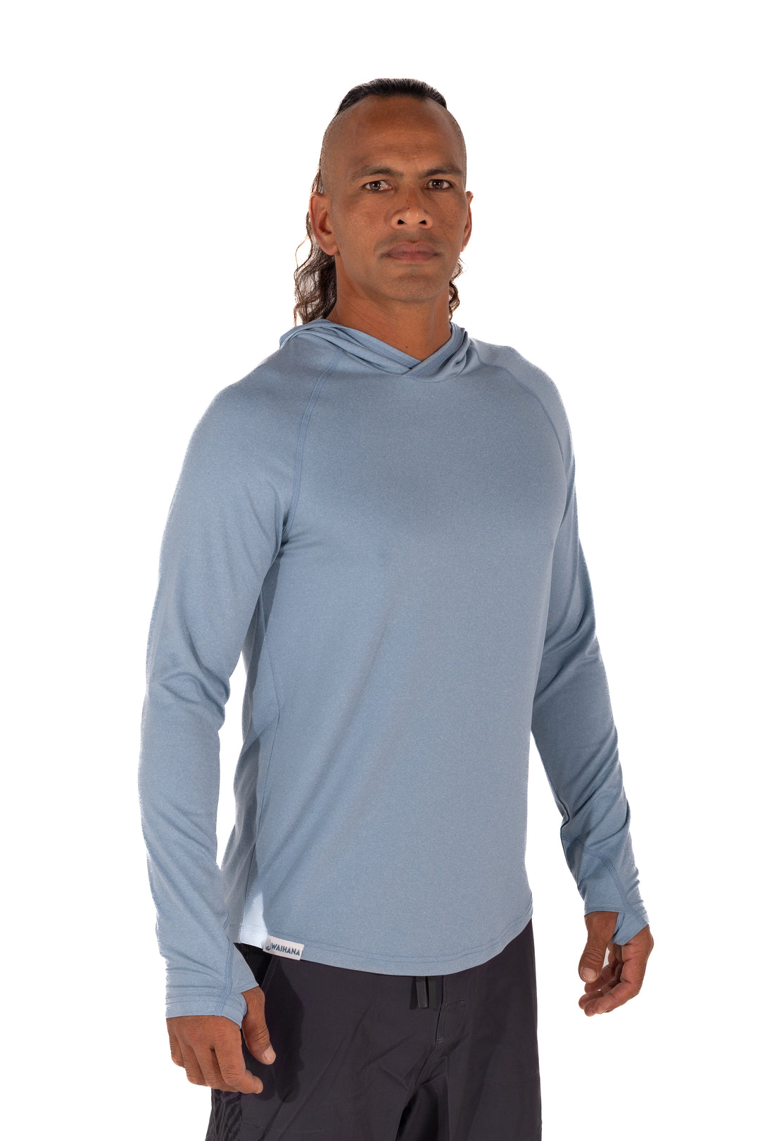 Male model wearing the Waihana Mariner Blue Hooded Long Sleeve sun shirt in light steel blue, featuring thumb holes and a relaxed fit, shown from a slight angle against a white background.