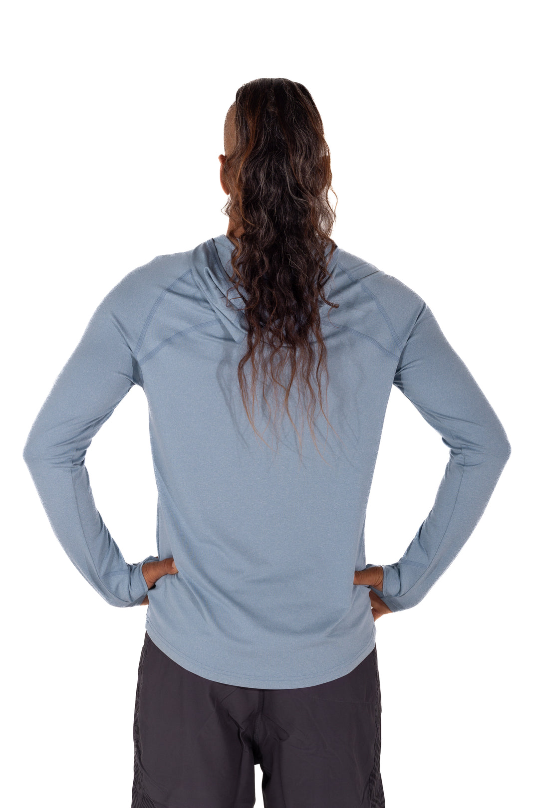 Back view of a model wearing the Waihana Mariner Blue Hooded Long Sleeve sun shirt in light blue with dark shorts, wet hair in a ponytail, on a white background.
